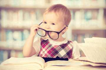 baby with glasses on reading a book
